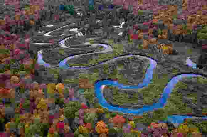 A Breathtaking Aerial View Of A Winding River Meandering Through A Lush Green Valley, Framed By The Towering Peaks Of Snow Capped Mountains. Natural Wonders Jim DeFelice